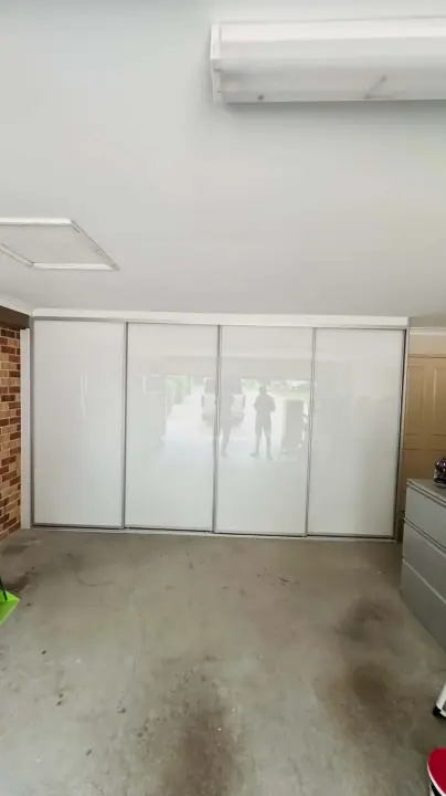 Wall of white glass sliding cupboards across the back of a garage