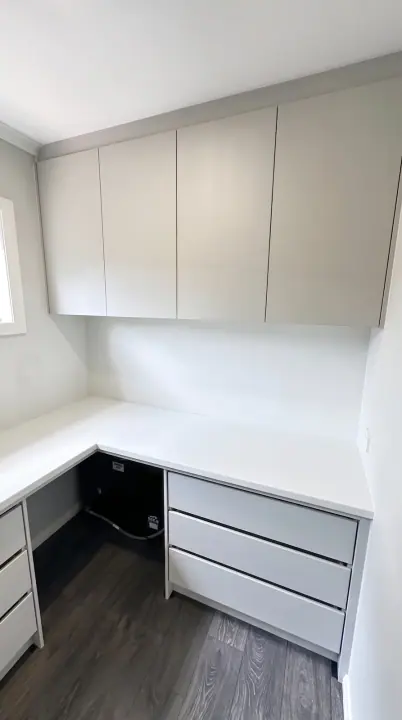 Corner home office with overhead cupboards and drawers
