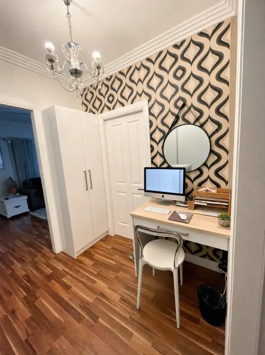 Home office with desk, mirror and patterned wallpaper