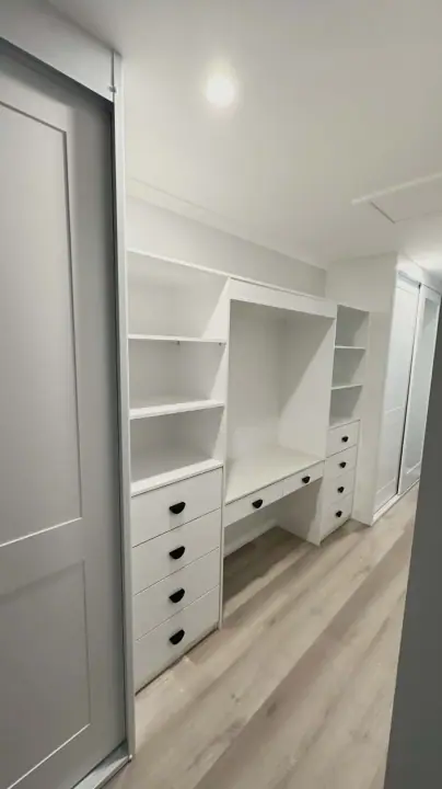 Sliding door open to a built-in desk with drawers and shelving