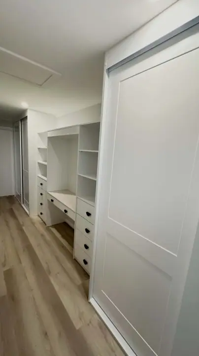 Shaker sliding doors open to a study desk and shelving