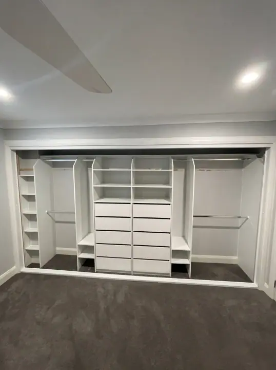 Wide wardrobe internals with a central drawer bank