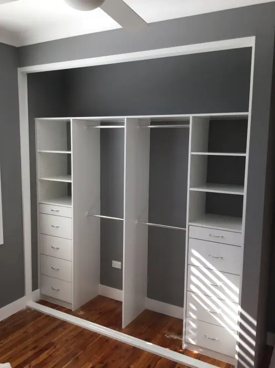 Wardrobe internals with shelves and drawers in a grey bedroom