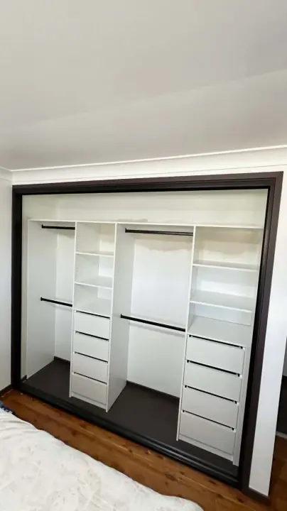 Black-framed sliding wardrobe with hanging, shelves and drawers inside