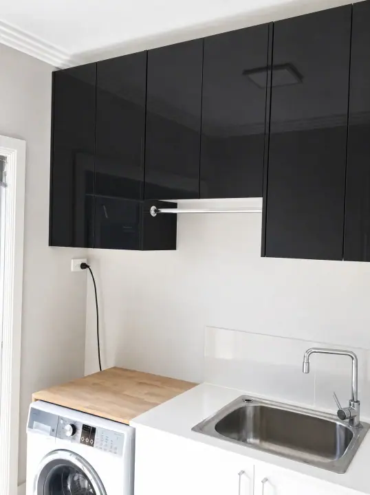 Laundry with black gloss overhead cupboards and a stainless sink