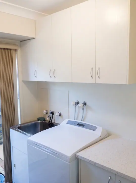 Laundry with white overheads and a bench over the washing machine