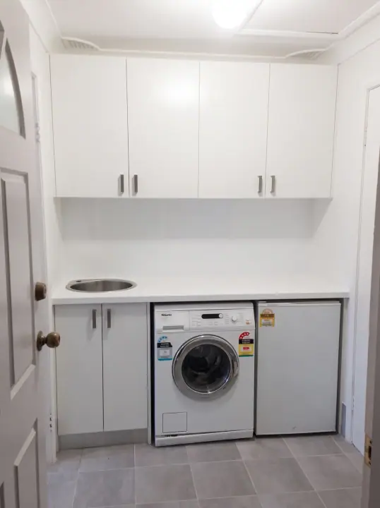 Compact laundry fit-out with white overhead cupboards