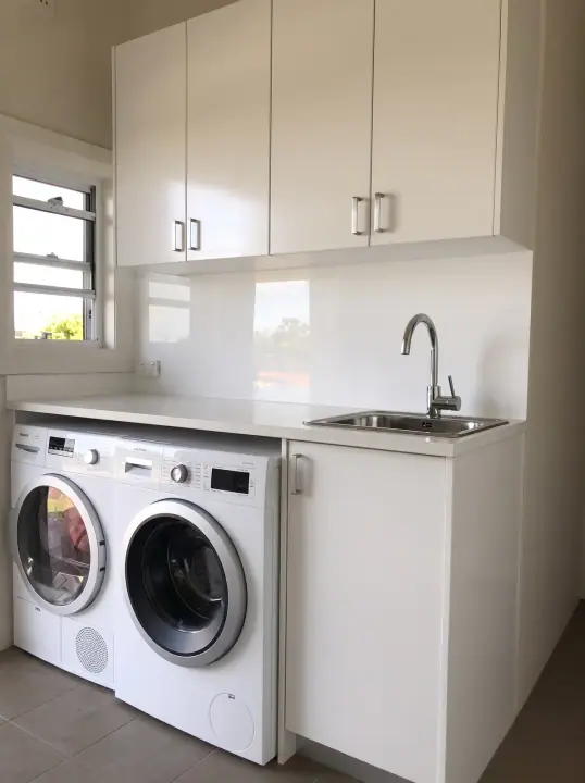 Laundry with white cupboards and space for washer and dryer