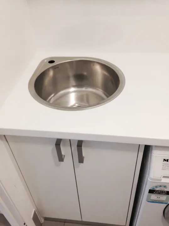Round stainless sink set into a white laundry bench