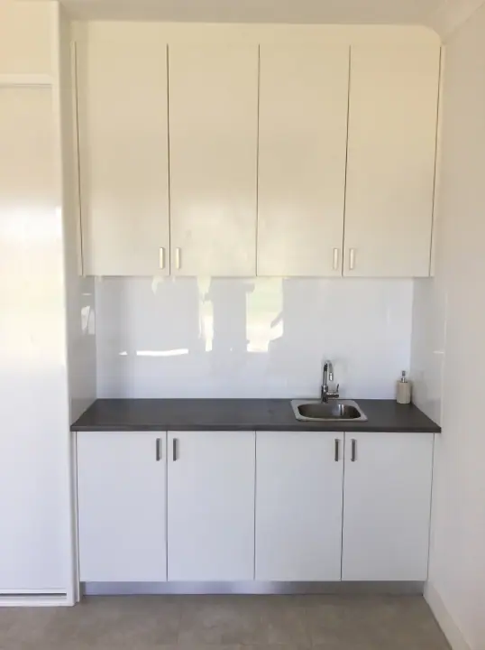 Laundry with white overheads, base cupboards and a dark benchtop