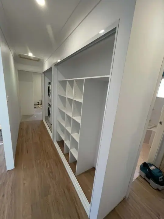 Hallway laundry revealed behind white glass sliding doors