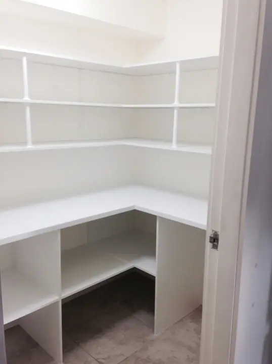 Corner pantry with deep shelving and a bench