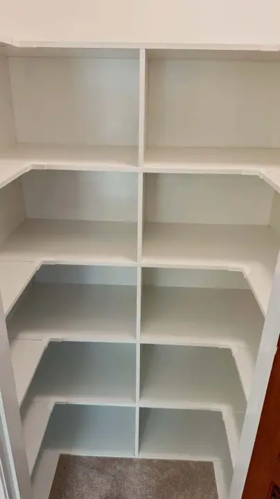 Corner linen cupboard with angled shelving that wraps the corner