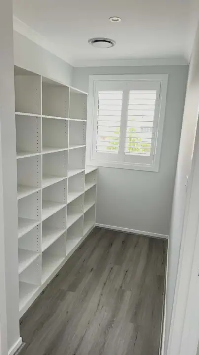 Walk-in store room shelved floor to ceiling, with a shuttered window