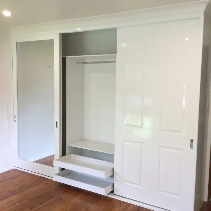 Sliding wardrobe with the doors open, showing the shelving and drawer bank inside