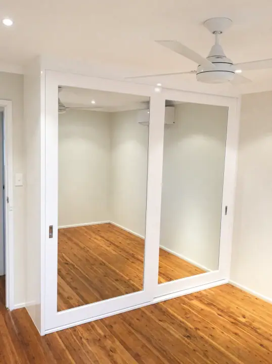 Mirrored sliding doors fitted neatly into a bedroom alcove