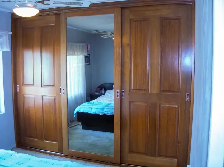 Dark timber-look sliding wardrobe doors with a mirrored centre panel