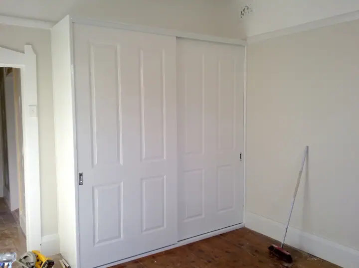 Four routed-panel sliding doors filling a bedroom wall
