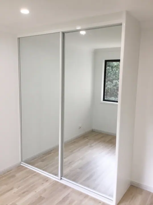 Two-door mirrored sliding wardrobe in a freshly painted bedroom