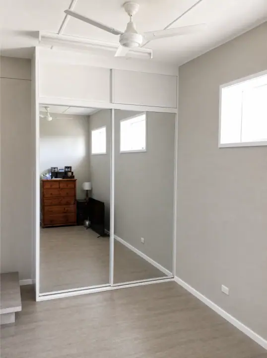 Mirrored sliding wardrobe fitted around a bedroom window