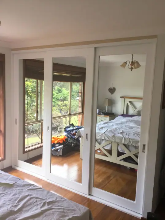 Mirror sliding doors reflecting a leafy garden view