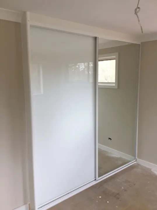 White glass and mirror sliding doors in a compact bedroom