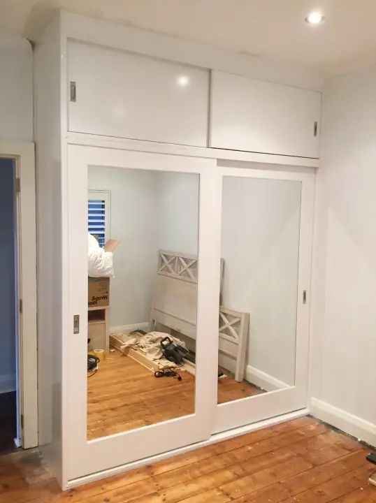 Mirror and white glass sliding doors during a bedroom fit-out