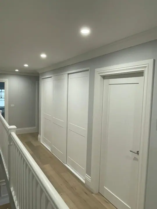 White panel sliding wardrobe on a landing with timber floors
