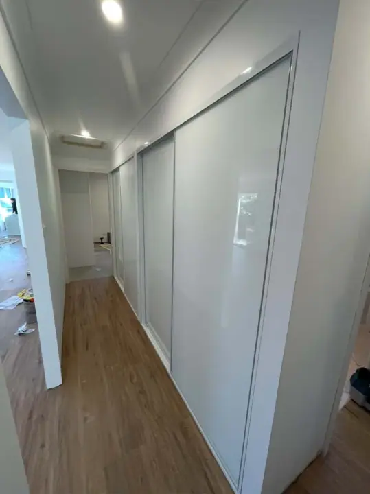 Run of white glass sliding doors along a hallway