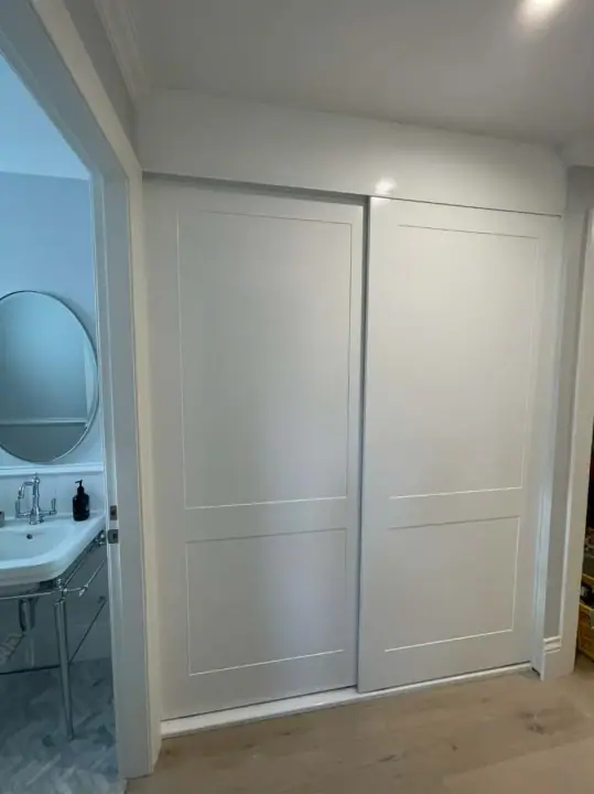 White shaker-profile sliding doors beside an ensuite