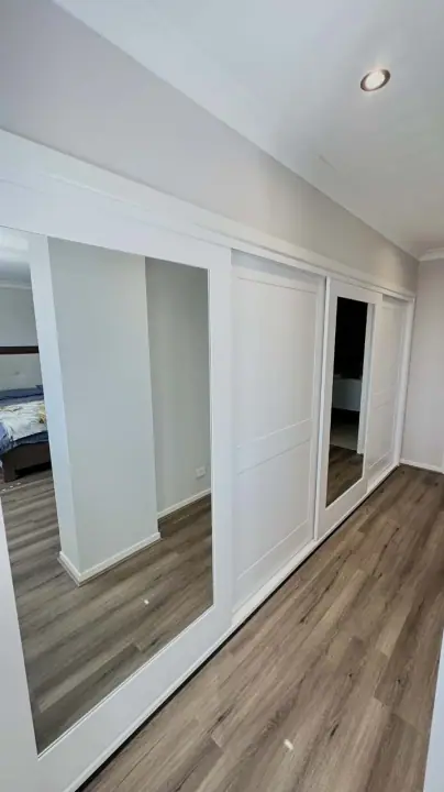 Two white panel doors and a mirror door in a bedroom with timber floors