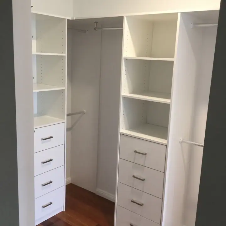 White walk-in wardrobe with a drawer tower and adjustable shelving