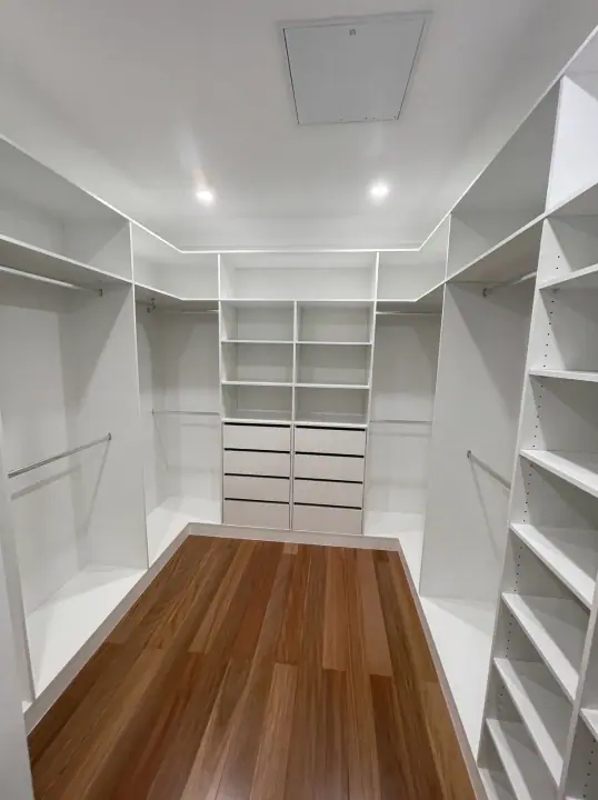 Walk-in fit-out with drawers and shelving over polished timber floors