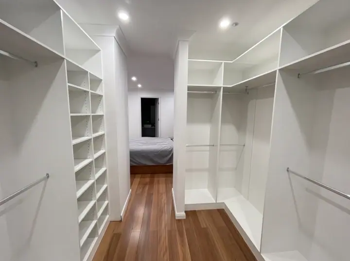 L-shaped walk-in wardrobe with open shelving and a shoe tower