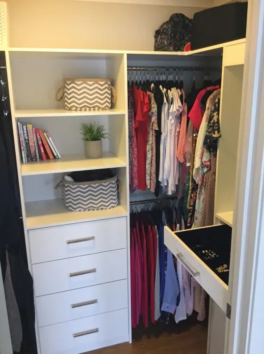 Walk-in wardrobe filled with hanging clothes, drawers and shelves