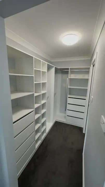 Walk-in wardrobe with shelving, hanging and a drawer bank under a round ceiling light