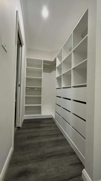 Compact walk-in with drawers and open shelving over dark timber floors
