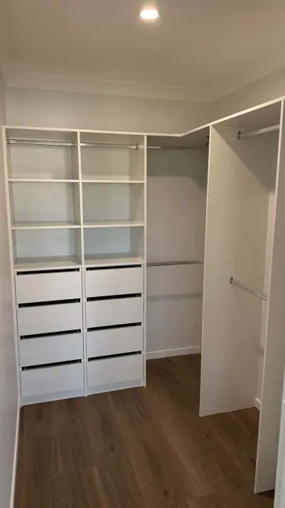 Walk-in wardrobe with a drawer tower, shelving and double hanging on timber floors