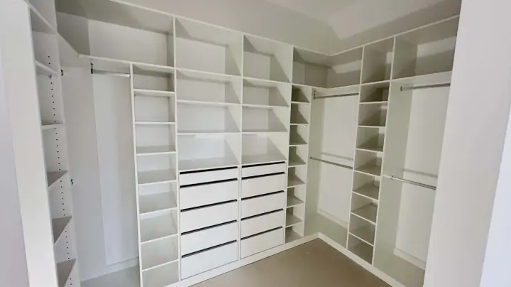 Corner walk-in with shelving, drawers and hanging on three walls