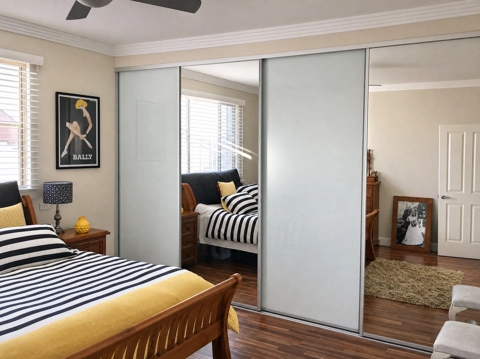 Four-door sliding wardrobe mixing white glass and mirror panels across a main bedroom wall, built by Reflections