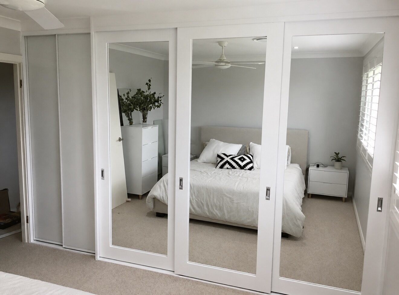 Mirrored sliding wardrobe making a compact Parramatta apartment bedroom feel larger