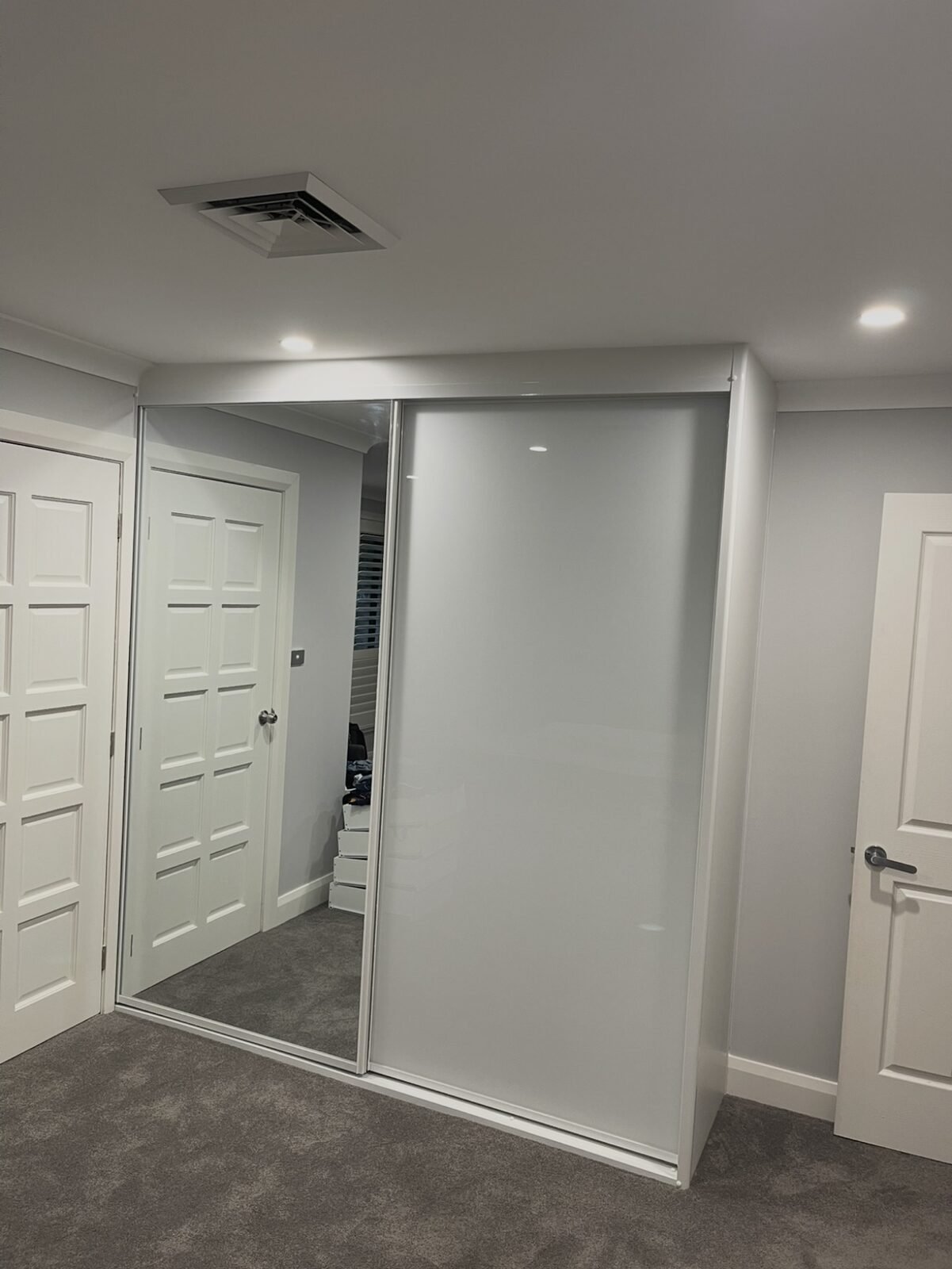 White glass sliding doors on a hallway storage cupboard