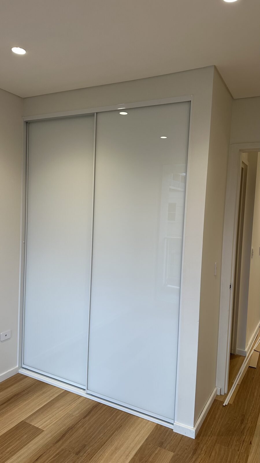 White glass sliding wardrobe doors in a bedroom